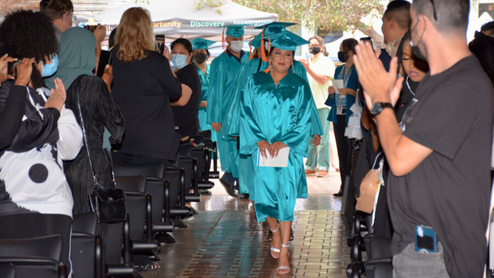 career online high school graduates walking down an aisle, surrounded by cheering people