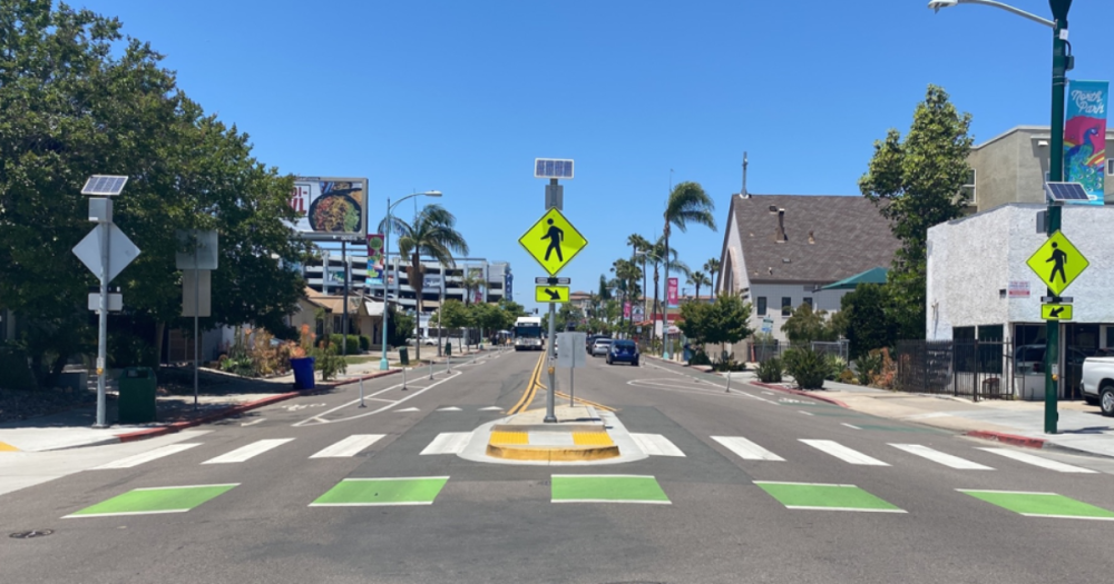 center view of a street with a bike lane and cross walk with safety lights.