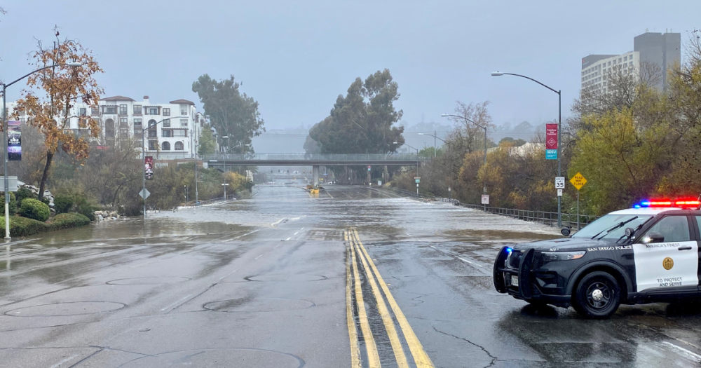 a flooded street being blocked off from a cop car.