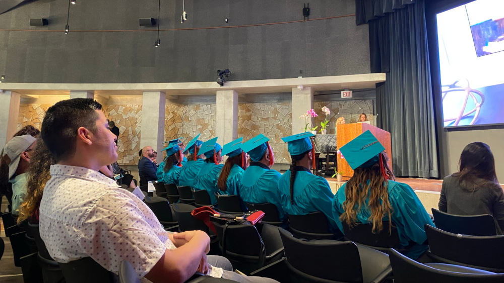 graduates and their families sitting in an auditorium facing the stage.