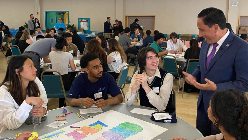 Mayor Gloria speaking with City interns at a table.
