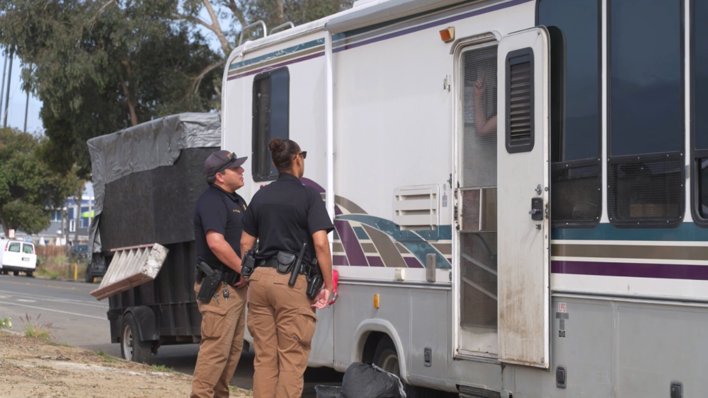 Two police officers standing by an RV
