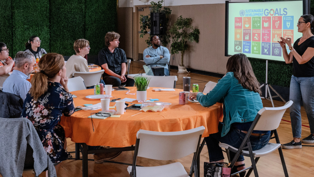 People sitting around a table with a presenter standing