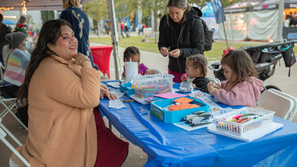 Children sitting at table making crafts at a park