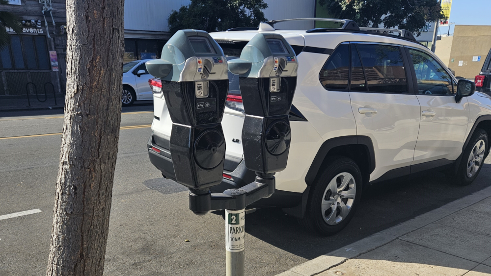 Two parking meters in front of a car