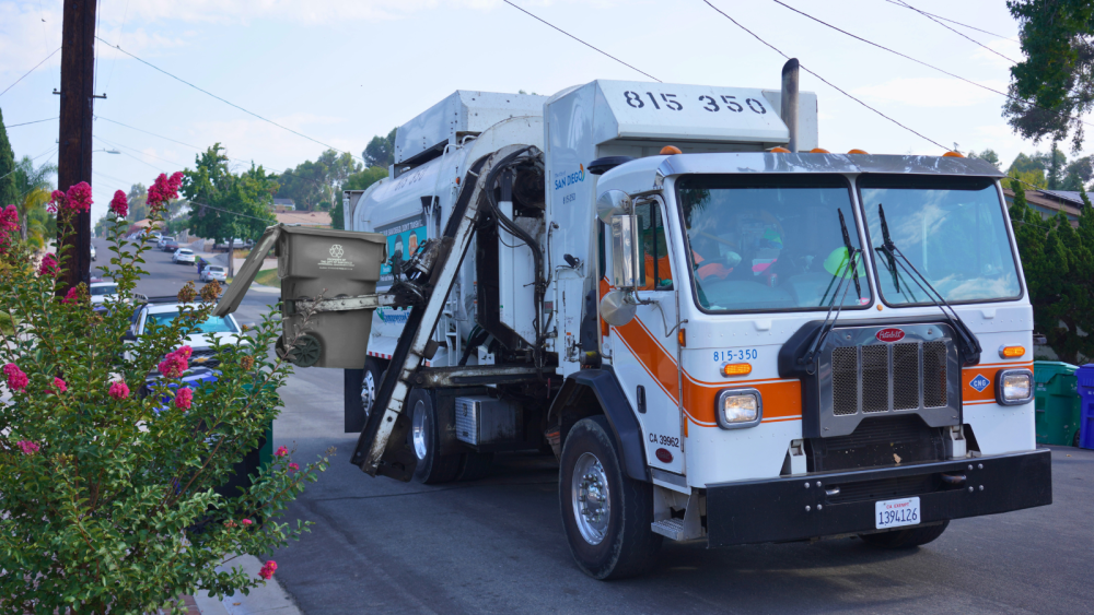 trash truck picking up gray trash bin