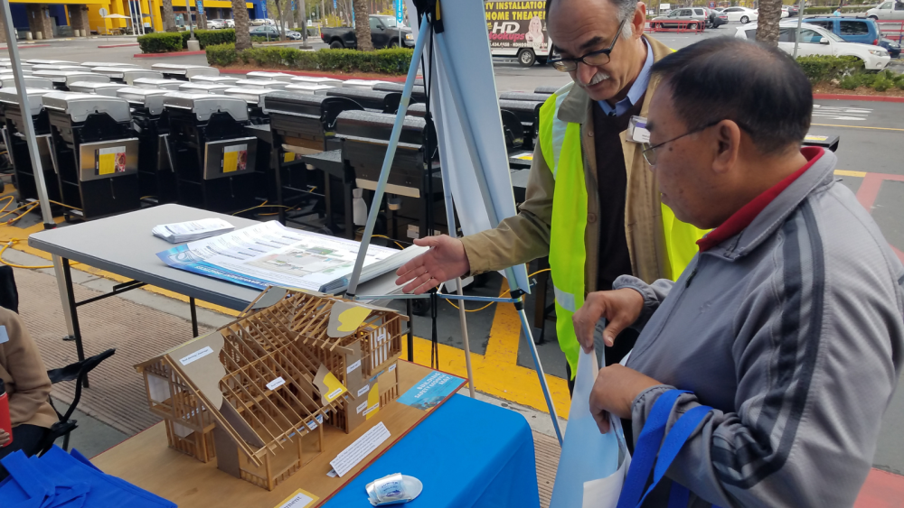 Two men standing by a small construction model of a building