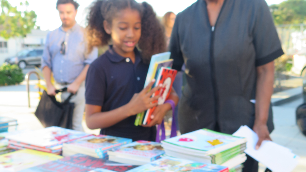 Child standing in front of table with books