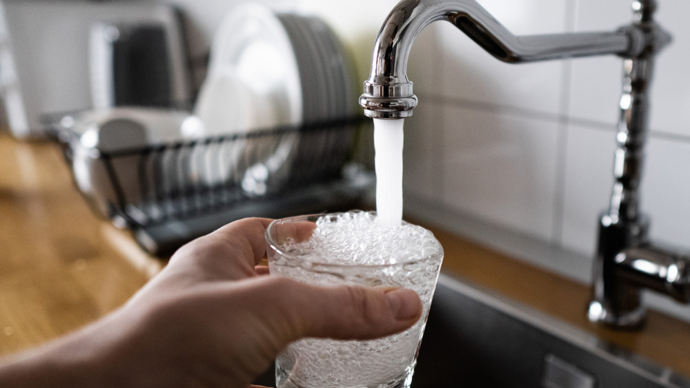 Hand holding cup being filled with water