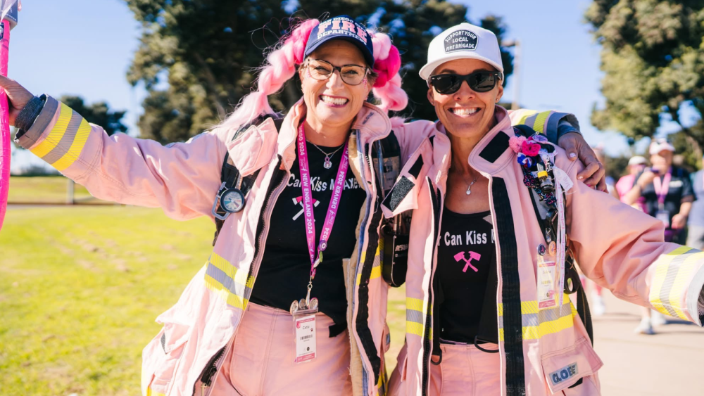 Two women smiling and hugging, dressed in pink