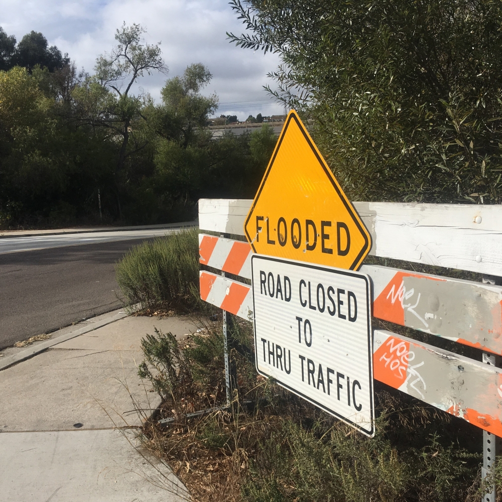 flooded sign on barricade located on the sidewalk
