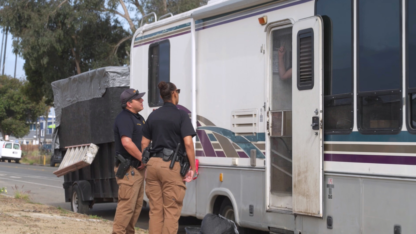 Two police officers standing by an RV