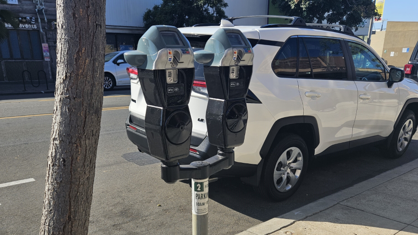 Two parking meters in front of a car