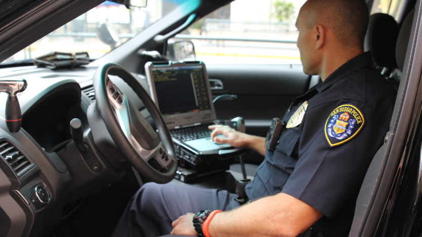 Photo of police officer in a car using a laptop