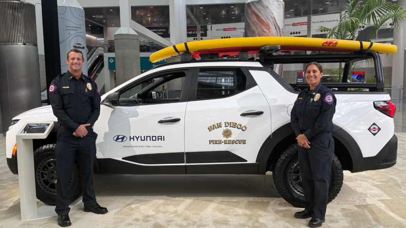 Two lifeguards posing in front of vehicle