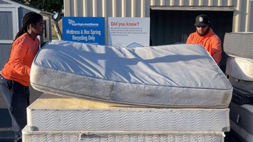 Two individuals dropping several mattresses