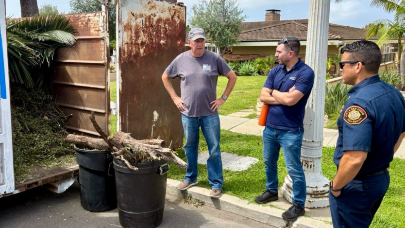 Three men standing next to bins