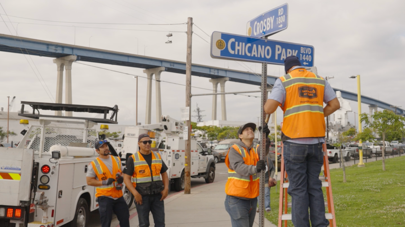 Four men install Chicano Park sign
