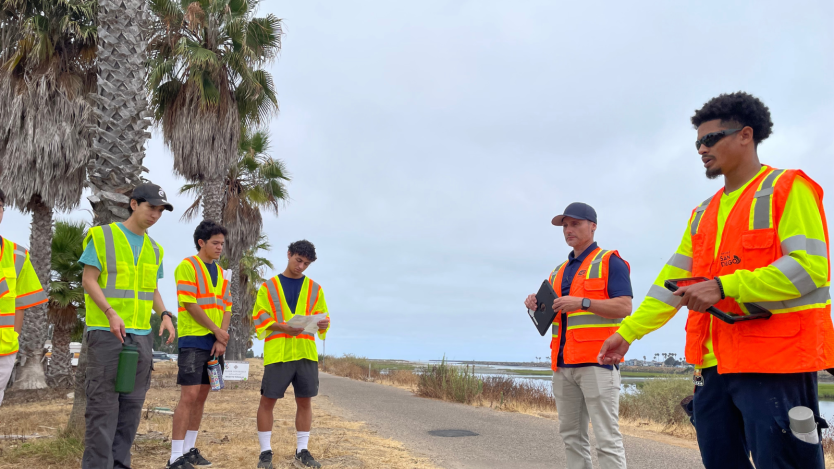 Three interns standing in yellow safety vests in front of two City staff