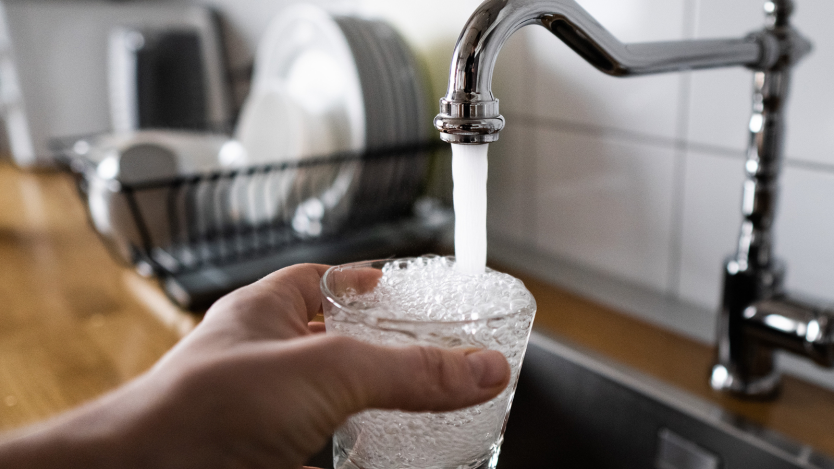 Hand holding cup being filled with water