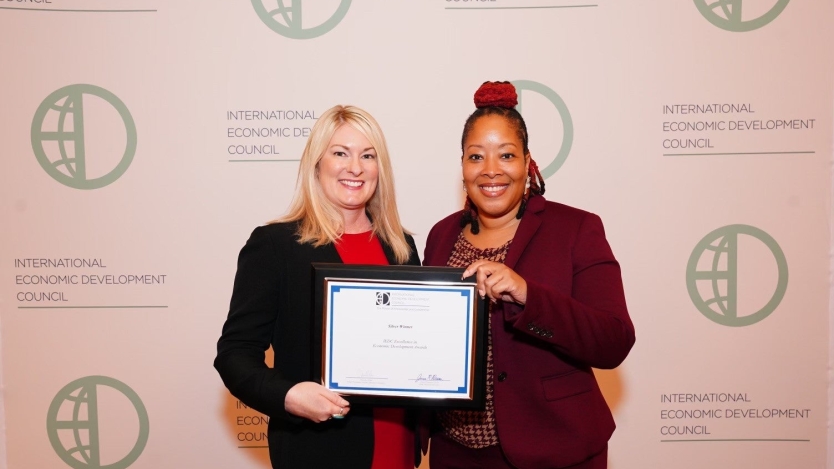 Two city employees holding award