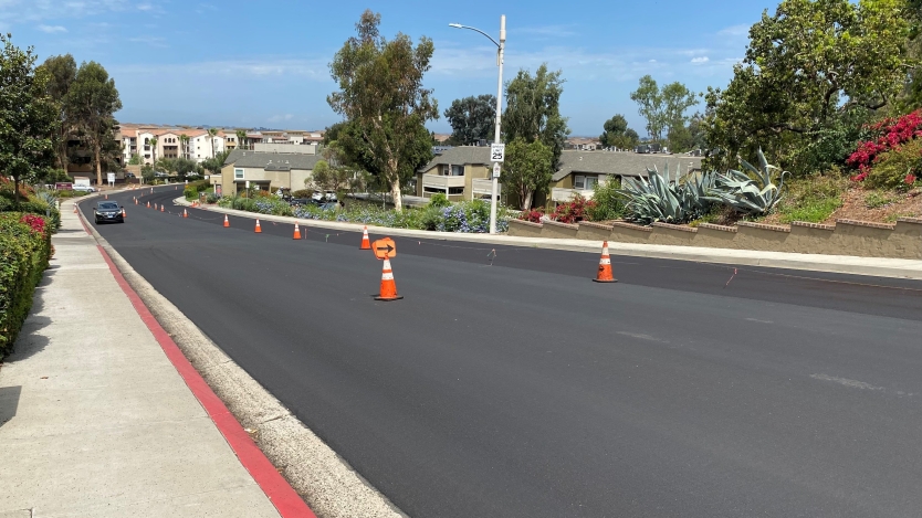 Freshly repaired and resurfaced road with traffic cones in the center